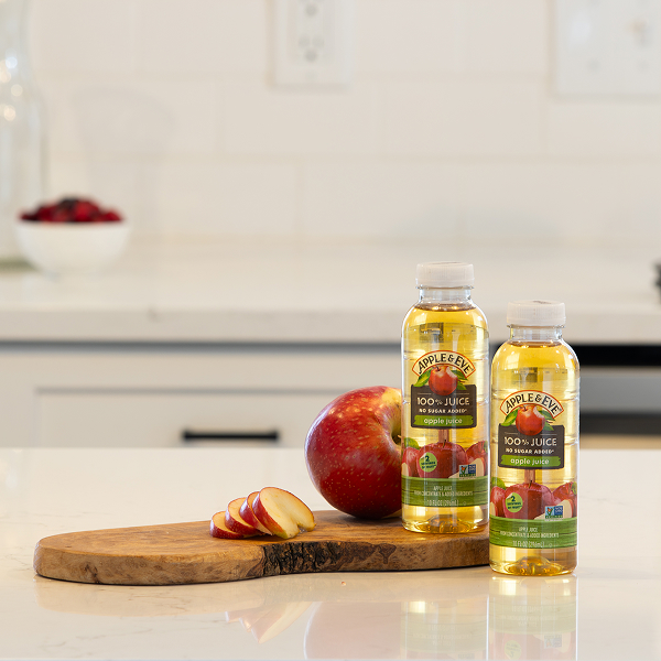 Apple Juice bottles on table next to apple fruit.