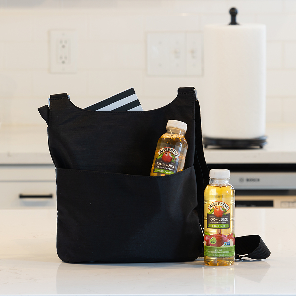 Apple Juice bottles on table and next to a bag.
