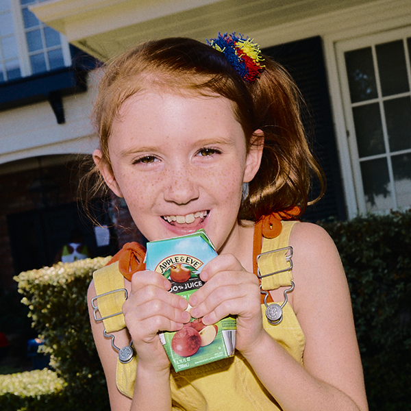 girl drinking a apple juice box with two hands
