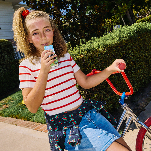 Girl drinking a juice box sitting on a bike