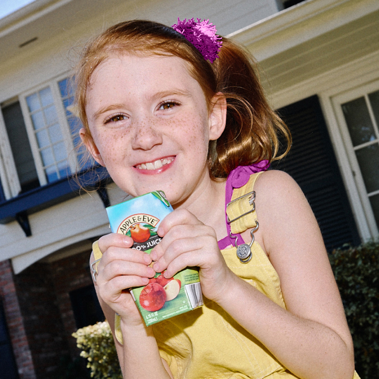 Child with glasses drinking an Apple and Eve apple juice box